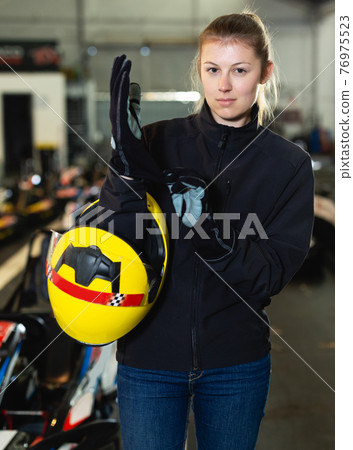 Young woman puts equipment for karting 76975523