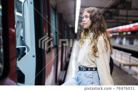 Woman entering the door of the modern train in subway 76976031