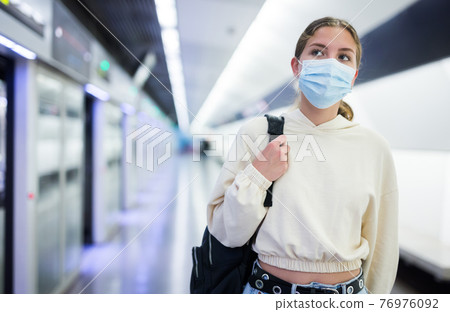 Young woman in face mask waiting for train Young woman in face mask waiting for train 76976092