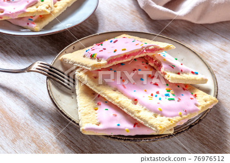 Strawberry pop tarts on a plate on a wooden table Strawberry pop tarts on a plate on a wooden table 76976512