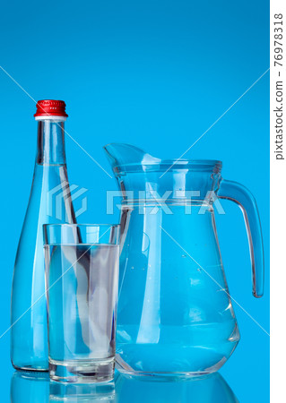 glassware filled with clean drinking water for health objects glass and jug with handle and bottle with lid still life on a blue background. 76978318
