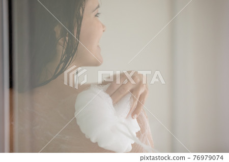 Happy young woman taking shower behind glass wall Happy young woman taking shower behind glass wall 76979074