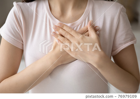 Grateful young woman applying hands on chest, expressing love 76979109