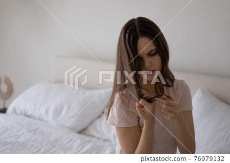 Upset young teenage girl dissatisfied dry long hair condition 76979132