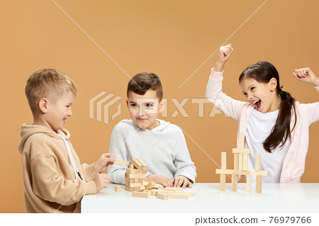 children plays with wooden constructor on desk. 76979766