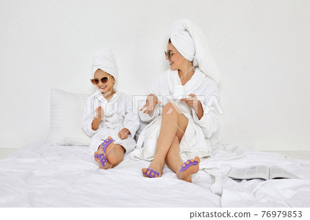 happy woman and her daughter in white bathrobes happy woman and her daughter in white bathrobes 76979853