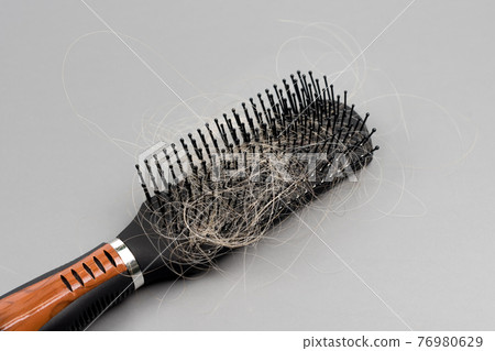 Hair loss problem, hairbrush with a lot of fallen hairs on grey background. Bunch of blonde hair on the comb. Losing too much hair. Healthcare concept. 76980629