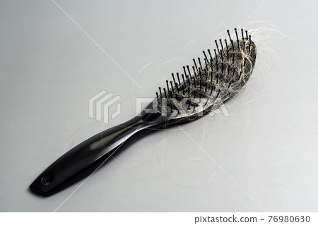 Hair loss problem, hairbrush with a lot of fallen hairs on grey background. Bunch of blonde hair on the comb. Losing too much hair. Healthcare concept. 76980630