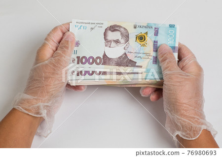 Stack of ukrainian hryvnia banknotes in gloved hands Stack of ukrainian hryvnia banknotes in gloved hands 76980693