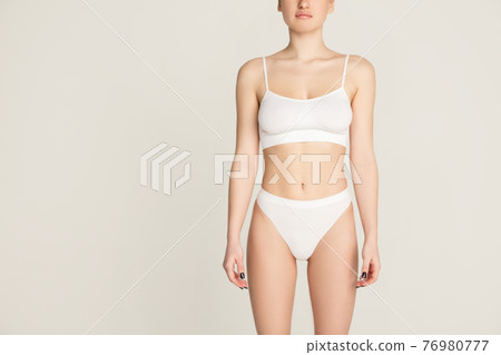 Beautiful female body in white underwear over light background. Beautiful female body in white underwear over light background. 76980777