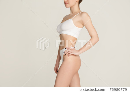 Cropped slim tanned beautiful woman in underwear isolated over gray background. Cropped slim tanned beautiful woman in underwear isolated over gray background. 76980779