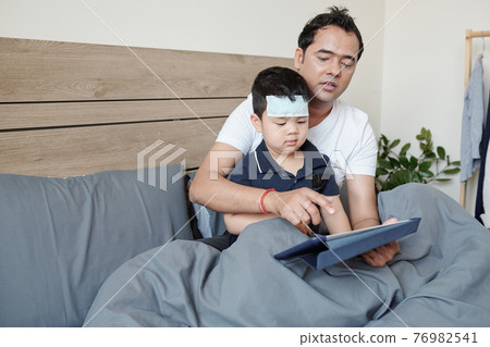 Father entertaining sick son 76982541