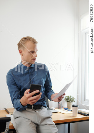 Serious businessman reading document 76982929