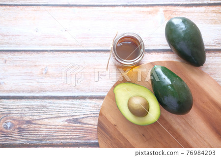 Top view of oil and slice of avocado on wooden table Top view of oil and slice of avocado on wooden table 76984203
