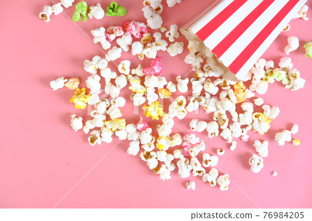 popcorn spilling from a container on pink background popcorn spilling from a container on pink background 76984205