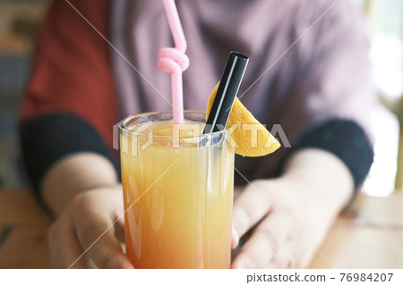 women hand holding a glass of orange juice women hand holding a glass of orange juice 76984207