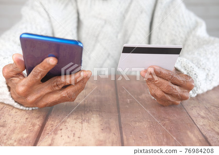 senior women hand holding credit card and using smart phone shopping online senior women hand holding credit card and using smart phone shopping online 76984208
