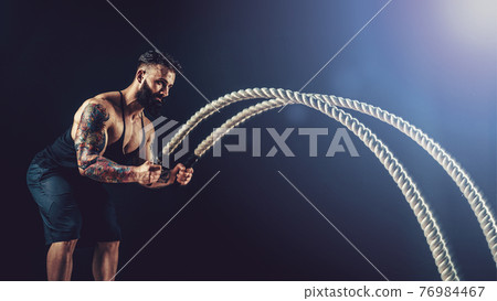 Muscular man working out with heavy rope. Photo of man with naked torso. Strength and motivation. Muscular man working out with heavy rope. Photo of man with naked torso. Strength and motivation. 76984467