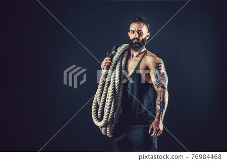 Muscular man working out with heavy rope. Photo of man with naked torso. Strength and motivation. Muscular man working out with heavy rope. Photo of man with naked torso. Strength and motivation. 76984468