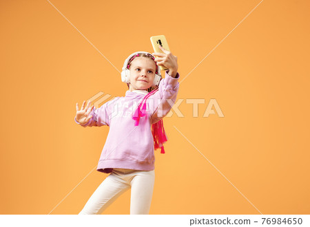 Pretty modern girl with pink dreadlocks in headphones smiling an Pretty modern girl with pink dreadlocks in headphones smiling an 76984650