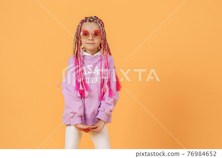 Stylish girl in rounded glasses with pink dreadlocks posing on a 76984652