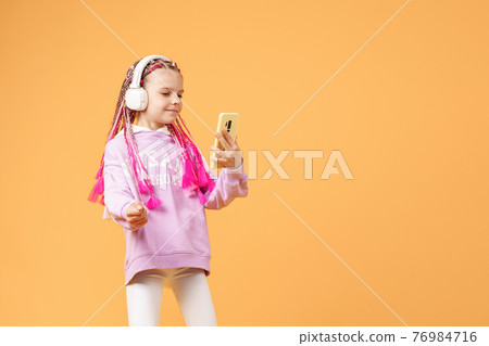 Pretty modern girl with pink dreadlocks in headphones smiling an Pretty modern girl with pink dreadlocks in headphones smiling an 76984716
