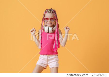Trendy DJ girl in bright clothes, headphones and bright dreadloc 76984760