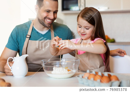 Dad And Daughter Cracking Eggs Making Dough For Cookies Indoors 76985378