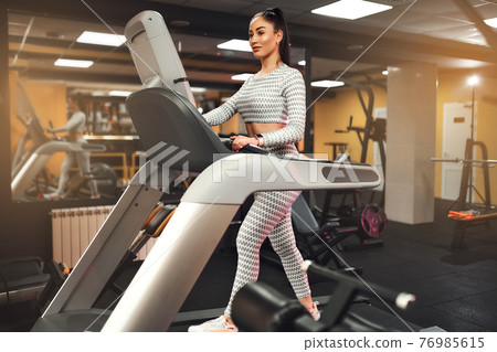Young healthy woman cardio on a treadmill at the gym  76985615