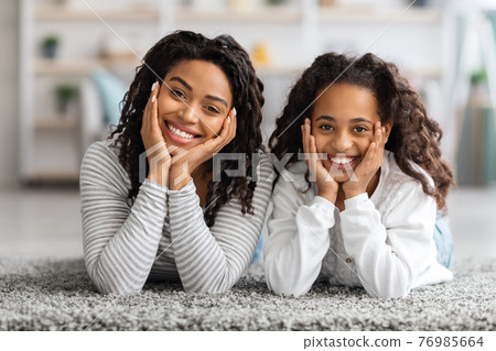 Adorable african american mother and daughter posing on carpet 76985664