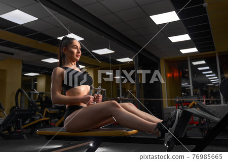 Muscular Fitness Woman Athlete Doing Heavy Weight Exercise For Back On Machine With Cable In The Gym 76985665