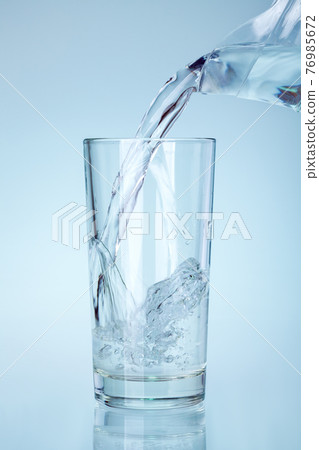 the clear glass is filled with water from the spout of the glass jug a stream of water with splashes and bubbles saturates and humidifies, nobody. the clear glass is filled with water from the spout of the glass jug a stream of water with splashes and bubbles saturates and humidifies, nobody. 76985672