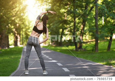 Fitness Training Outdoors. Full-length shot of sporty female warming up before running Fitness Training Outdoors. Full-length shot of sporty female warming up before running 76985739