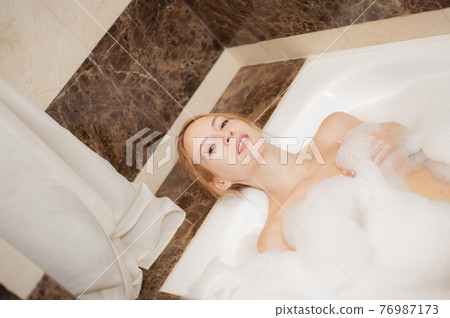 Young happy beautiful blond wooman into bath tube Young happy beautiful blond wooman into bath tube 76987173