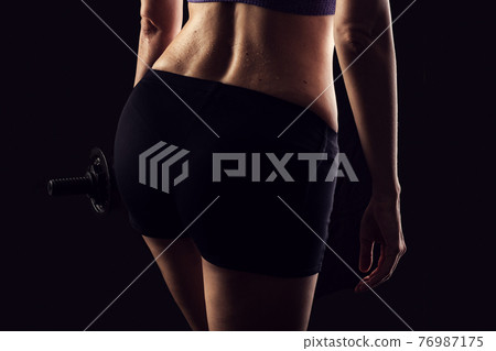 Slim athletic woman Holding dumbbell in the hand Slim athletic woman Holding dumbbell in the hand 76987175