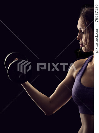 Slim athletic woman Holding dumbbell in the hand Slim athletic woman Holding dumbbell in the hand 76987186