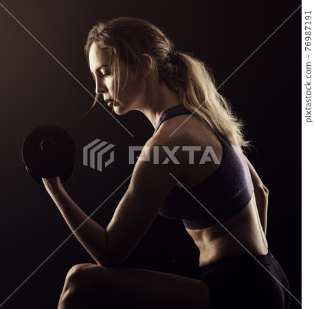 Slim athletic woman Holding dumbbell in the hand Slim athletic woman Holding dumbbell in the hand 76987191