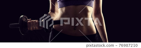 Slim athletic woman Holding dumbbell in the hand Slim athletic woman Holding dumbbell in the hand 76987210