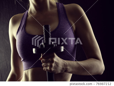 Slim athletic woman Holding dumbbell in the hand Slim athletic woman Holding dumbbell in the hand 76987212