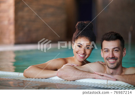 Portrait of young couple in swimming pool, looking at camera. Portrait of young couple in swimming pool, looking at camera. 76987214