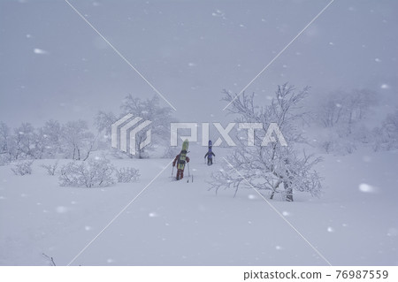 A snowboarder entering a raging snowy mountain A snowboarder entering a raging snowy mountain 76987559