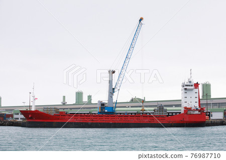 Cargo ship with red hull is loading in port 76987710
