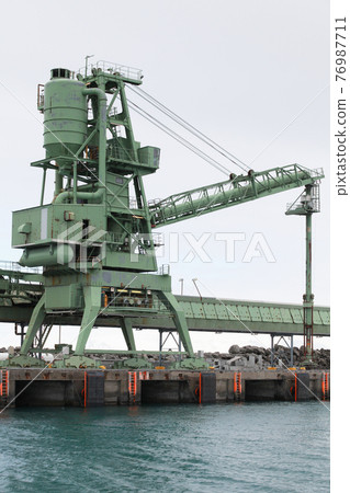 Green bulker crane is near transporter 76987711
