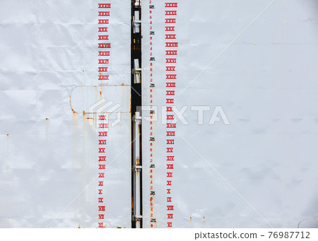 Tide gauge marking is on gray dry dock hull 76987712