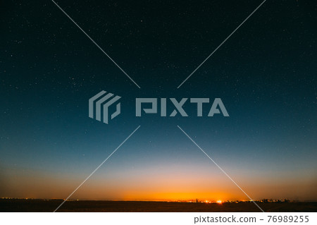 Night Starry Sky Over Yellow Sunset Or Sunrise Lights. Night Glowing Stars. Dark Night Starry Sky Over Ground In Warm Yellow Colors. Copyspace Space Abstract Landscape Background 76989255