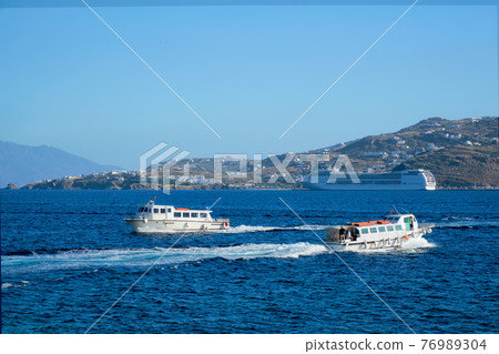 Boat and cruise liner is Aegean sea. Chora, Mykonos island, Greece 76989304