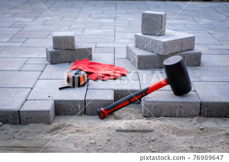 The master in yellow gloves lays paving stones 76989647