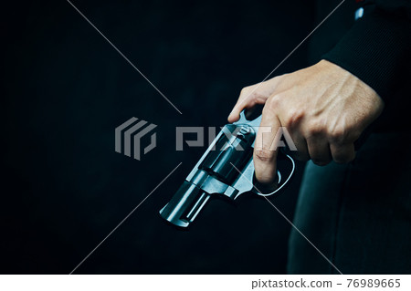Black revolver with drum in man's hand. 76989665