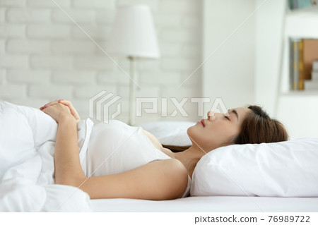Beautiful Attractive Asian woman sleep and sweet dream lying on bed in cozy bedroom in the morning feeling so relax and comfortable,Healthcare Concept 76989722