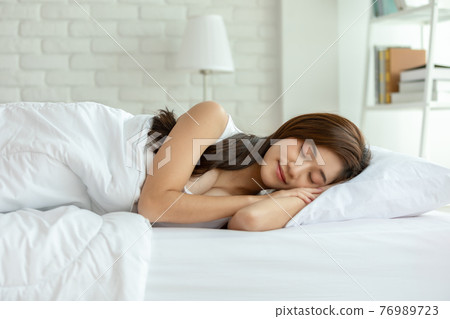 Beautiful Attractive Asian woman sleep and sweet dream lying on bed in cozy bedroom in the morning feeling so relax and comfortable,Healthcare Concept 76989723